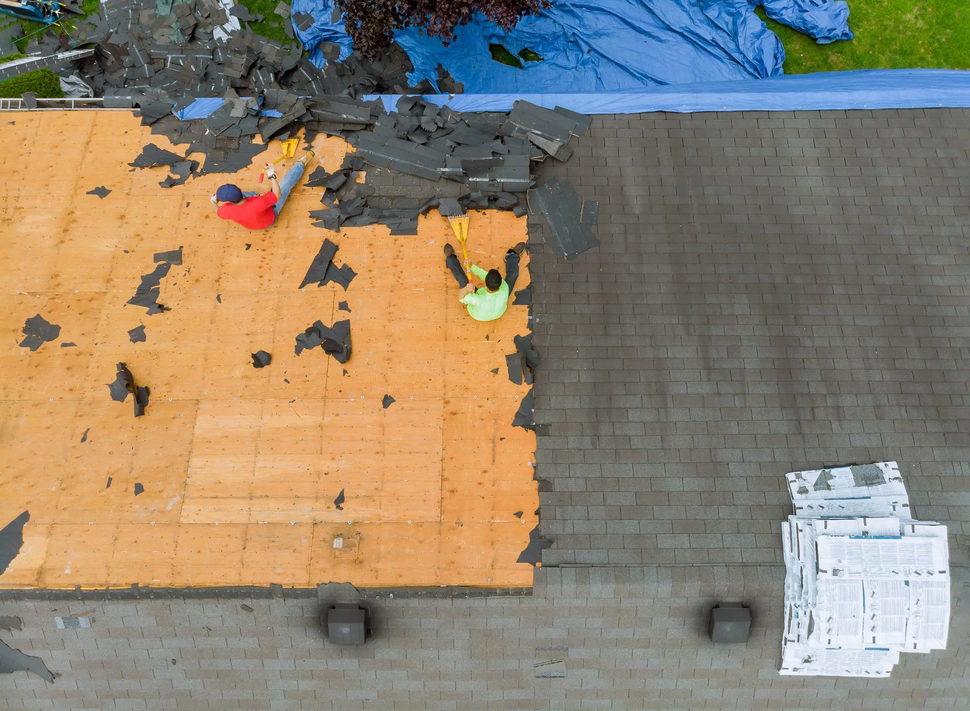 An aerial view captures roofers replacing shingles on a house