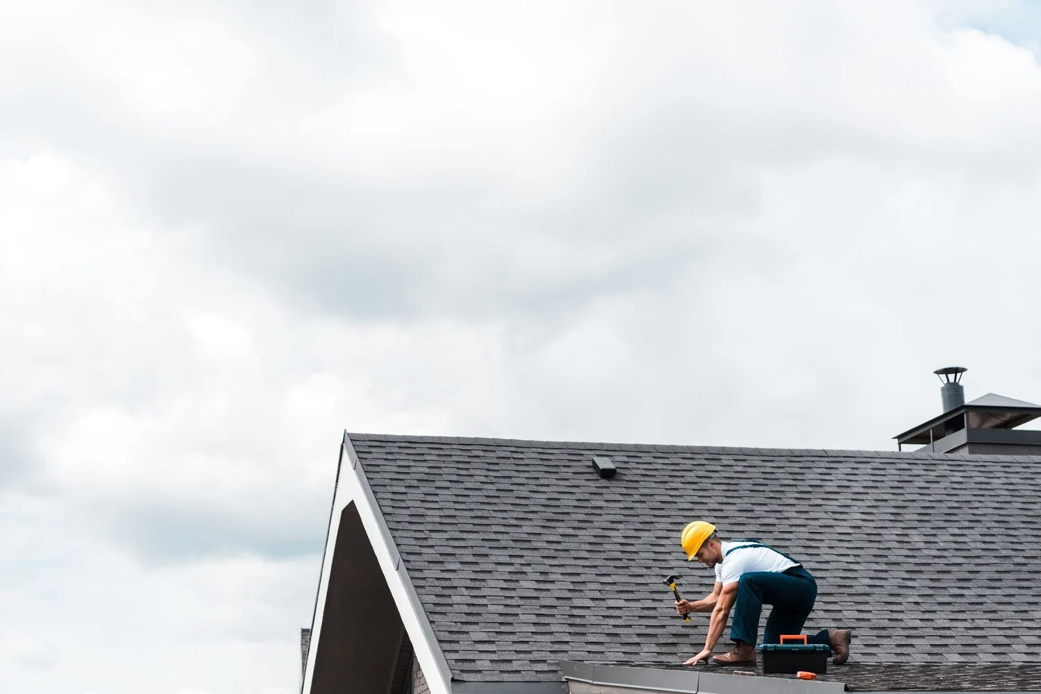 A man repairing a roof holding a hammer in one hand